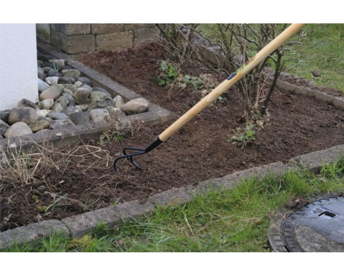 Záhradná scéna s kultivátorom s drevenou rukoväťou pri obrábaní pôdy