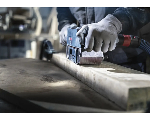 Remeselník brúsi drevo pásovou brúskou