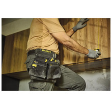 Remeselník s puzdrom na náradie a zvinovacím metrom pri montáži drevených skríň