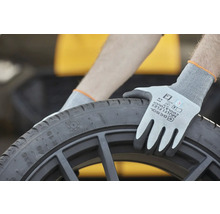 Osoba s ochrannými rukavicami drží čiernu pneumatiku.