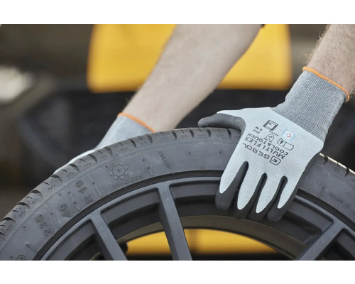 Osoba s ochrannými rukavicami drží čiernu pneumatiku.