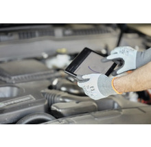 Mechanik s ochrannými rukavicami používa tablet pri motore auta.