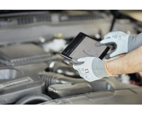 Mechanik s ochrannými rukavicami používa tablet pri motore auta.