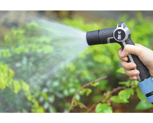 Ruka drží záhradnú striekaciu pištoľ a zalieva rastliny.