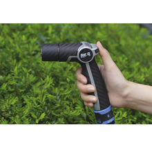 Záhradná striekacia pištoľ v ruke pred kríkmi