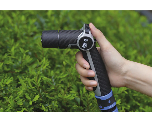 Ruka drží záhradnú striekaciu pištoľ značky For Q pred zeleným kríkom