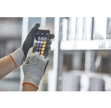 Osoba v pracovných rukaviciach používa kalkulačku na smartfóne.