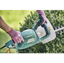 Osoba používa elektrické nožnice na živý plot na úpravu živého plota.