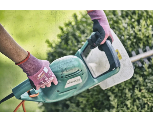 Osoba používa elektrické nožnice na živý plot na úpravu živého plota.