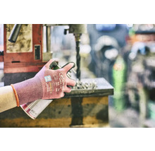 Osoba pracuje s vŕtačkou a nosí pracovné rukavice na ochranu.