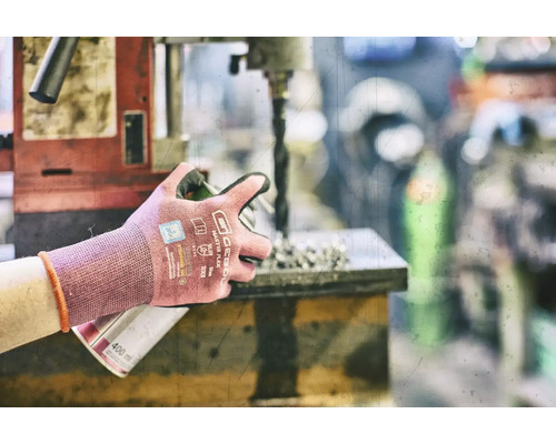 Osoba pracuje s vŕtačkou a nosí pracovné rukavice na ochranu.