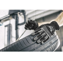 Osoba v pracovných rukaviciach drží pneumatiku.