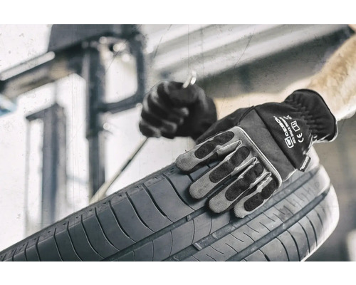 Osoba v pracovných rukaviciach drží pneumatiku.