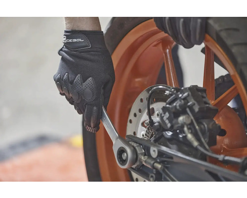 Osoba v rukaviciach používa kľúč na motocykli.