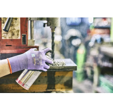 Osoba s ochrannými rukavicami drží plechovku s rozprašovačom pri vŕtačke.