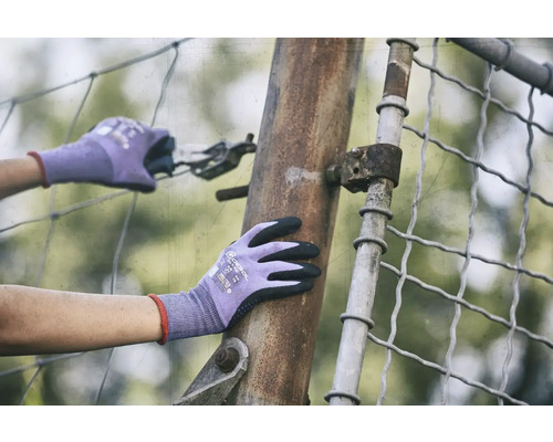 Osoba v rukaviciach pracuje s kliešťami na kovovom plote.