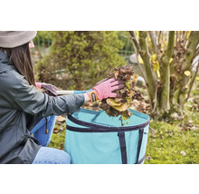 Žena vysýpa lístie do záhradného textilného vreca.