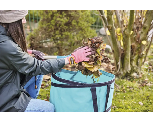 Žena vysýpa lístie do záhradného textilného vreca.