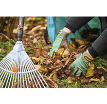 Osoba s hrabľami na lístie a záhradnými rukavicami odstraňuje lístie