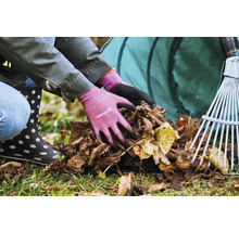 Osoba v záhradných rukaviciach zbiera lístie s hrabľami a vakom na lístie v pozadí