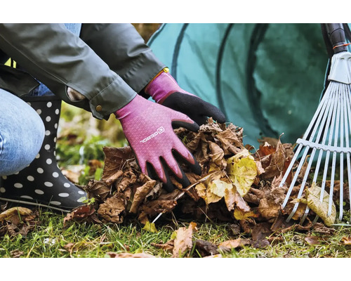 Osoba v záhradných rukaviciach zbiera lístie s hrabľami a vakom na lístie v pozadí