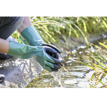 Osoba s vodotesnými záhradnými rukavicami čistí záhradné jazierko