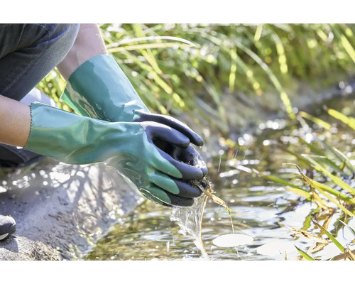 Osoba s vodotesnými záhradnými rukavicami čistí záhradné jazierko