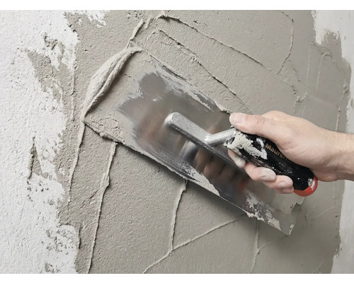 Murár omieta stenu hladidlom