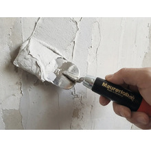 Remeselník s murárskou lyžicou nanáša omietku na stenu. Logo Maurerlob.