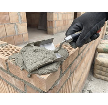 Murárska ruka s lyžicou nanáša maltu na tehly