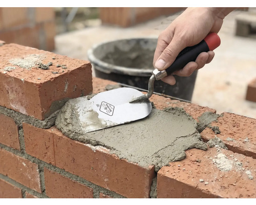 Murárske práce: Tehla sa škáruje maltou a murárskou lyžicou.