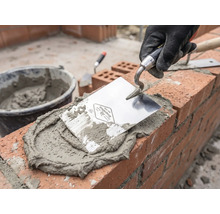 Murár pri práci s lyžicou, maltou a tehlami