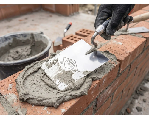 Murár pri práci s lyžicou, maltou a tehlami