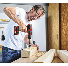 Muž vŕta otvor do kusu dreva pomocou akumulátorového skrutkovača