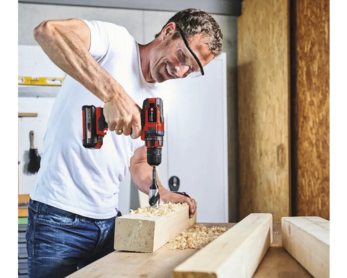 Muž vŕta otvor do kusu dreva pomocou akumulátorového skrutkovača