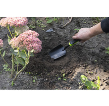 Záhradná scéna s rukou, ktorá zapichuje sadzačku do zeme