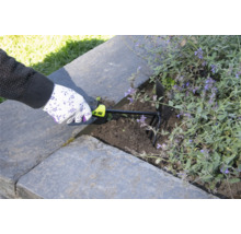 Osoba používa záhradný kultivátor na prekyprenie pôdy vo vyvýšenom záhone.