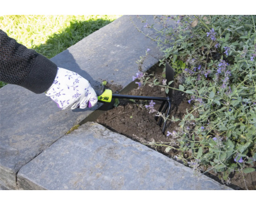 Osoba používa záhradný kultivátor na prekyprenie pôdy vo vyvýšenom záhone.