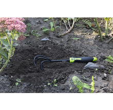 Záhradné hrable v zemi vedľa kvetiny