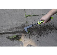 Osoba odstraňuje burinu zo škár dlažby pomocou škrabky na škáry.