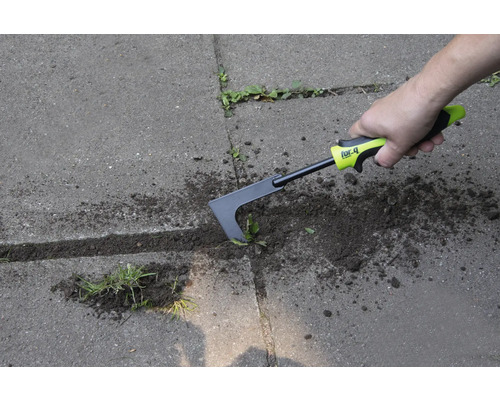 Osoba odstraňuje burinu zo škár dlažby pomocou škrabky na škáry.