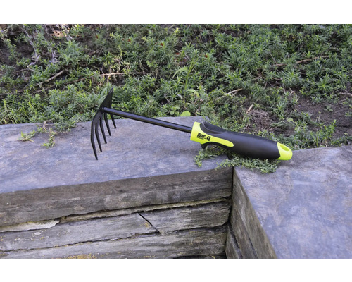 Hrabla na lístie a záhradné hrable s hrotmi a plastovou rukoväťou na kamennom múre