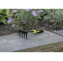 Záhradné hrable s piatimi hrotmi pred kvetinovým záhonom