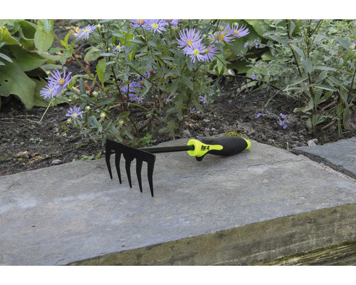 Záhradné hrable s piatimi hrotmi pred kvetinovým záhonom