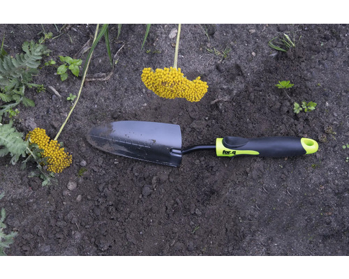 Záhradná lopatka so žltým kvetenstvom v záhradnom záhone