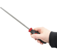 Ruka drží kľúčový pilník s plastovou rukoväťou.