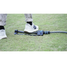 Záhradný zavlažovač na trávniku s nohou na porovnanie veľkosti.