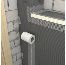 Aplikácia bielej mriežkovej pásky na spoje sivých stavebných dosiek na murovanej stene.