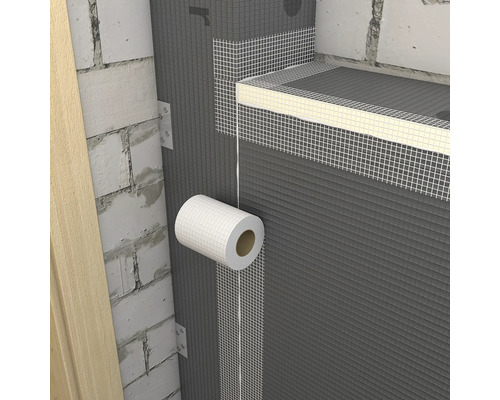 Aplikácia bielej mriežkovej pásky na spoje sivých stavebných dosiek na murovanej stene.