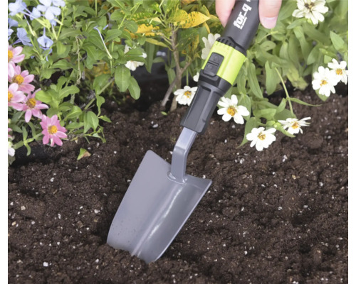 Ruka používa sadzaciu lopatku for_q na kopanie v zemine v kvetinovom záhone.